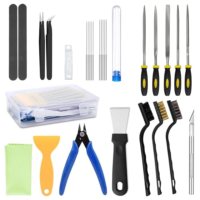 Set disposto: bastoncini abrasivi, pinzette, aghi in un tubetto, cinque lime, una scatola trasparente, panno, raschietti in plastica e acciaio, tronchesino, spazzole e un taglierino da modellismo