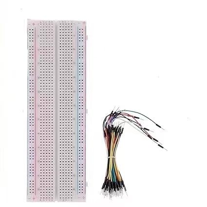 Lunga breadboard bianca senza saldatura con linee dei binari rosse e blu su entrambi i bordi, accanto a un fascio di cavetti jumper flessibili